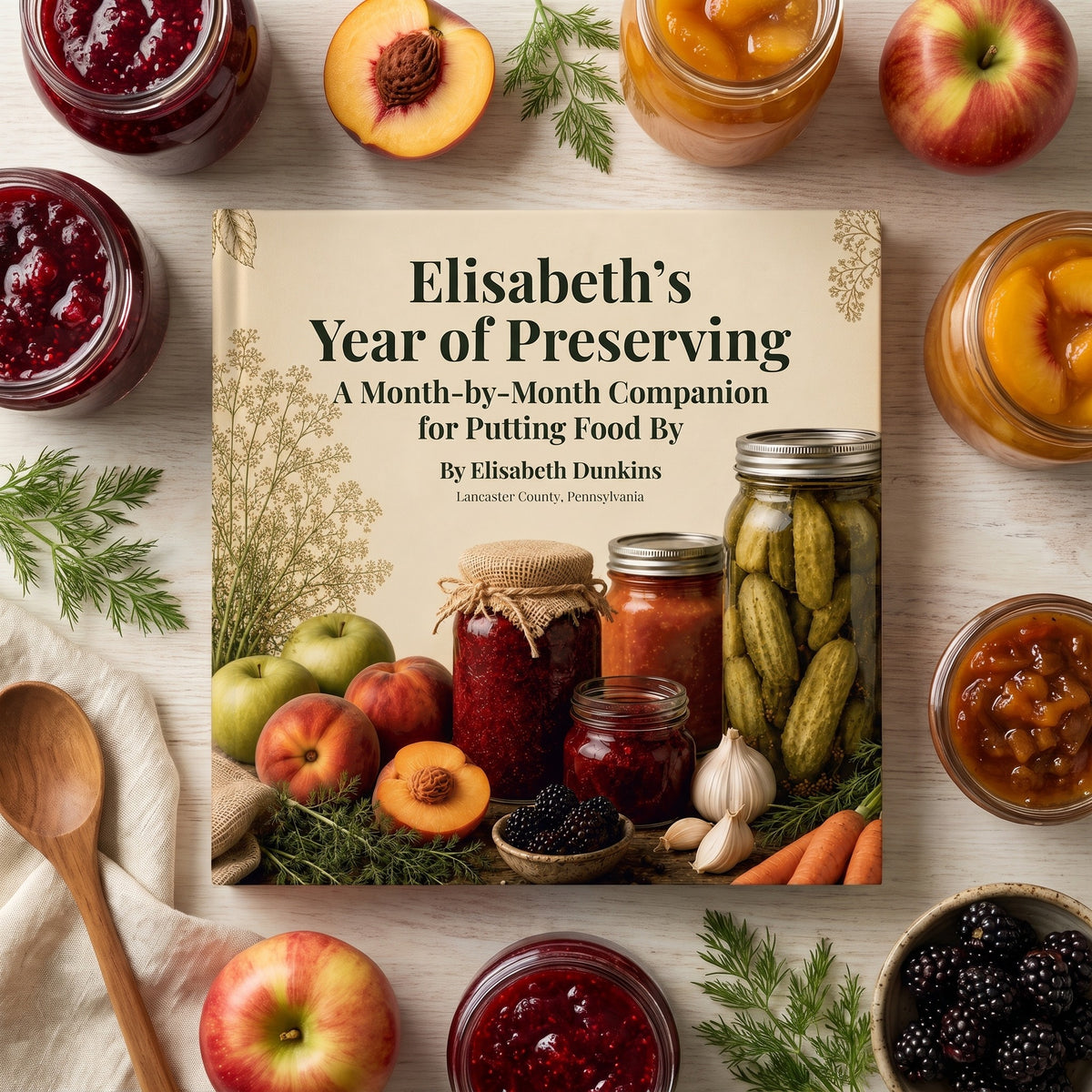 The Preserving Year, Written Down hardcover seen from above, surrounded by jars of home preserves, fresh fruit and herbs