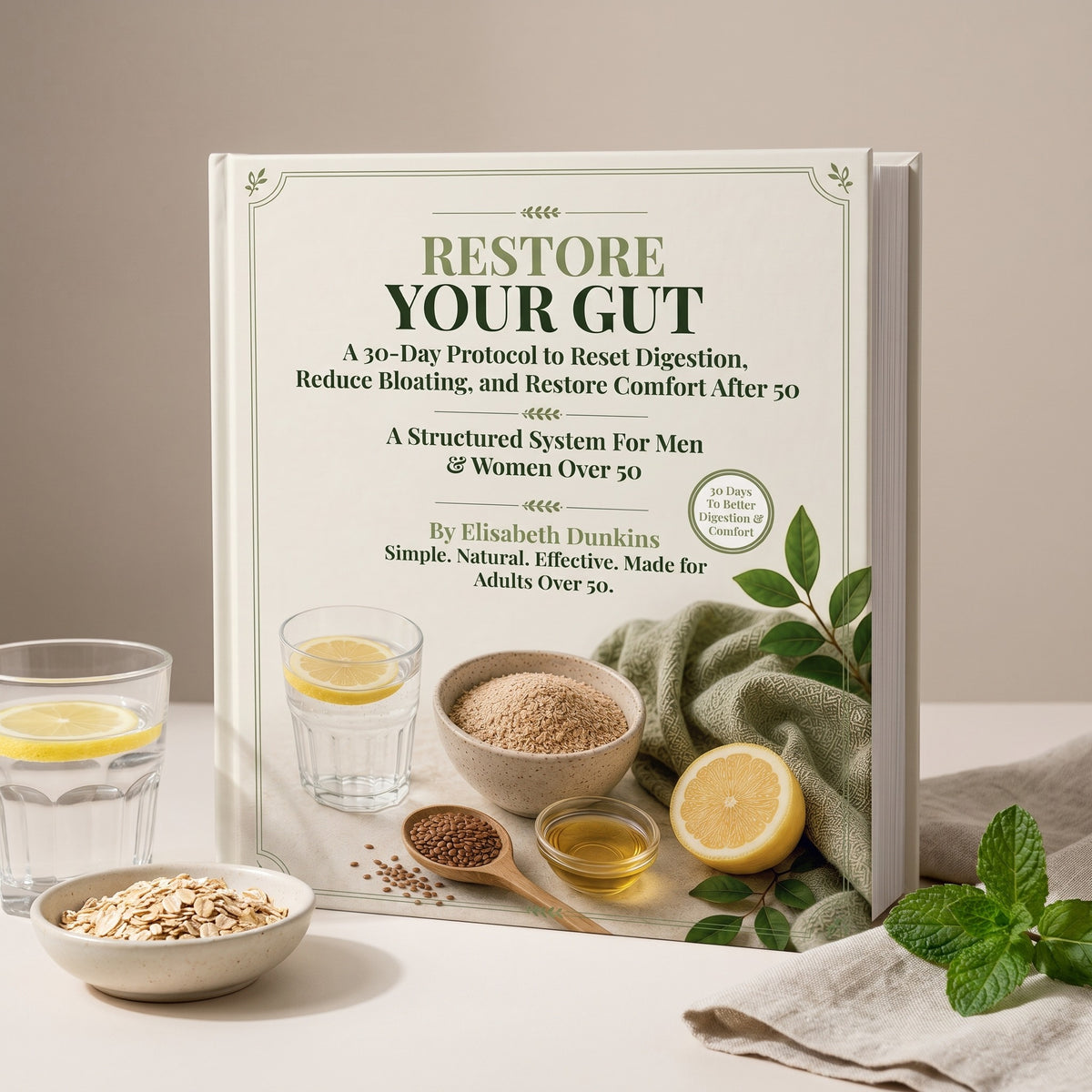 Restore Your Gut Blueprint hardcover standing on a pale surface beside lemon water, a bowl of oats and flaxseed, and fresh mint
