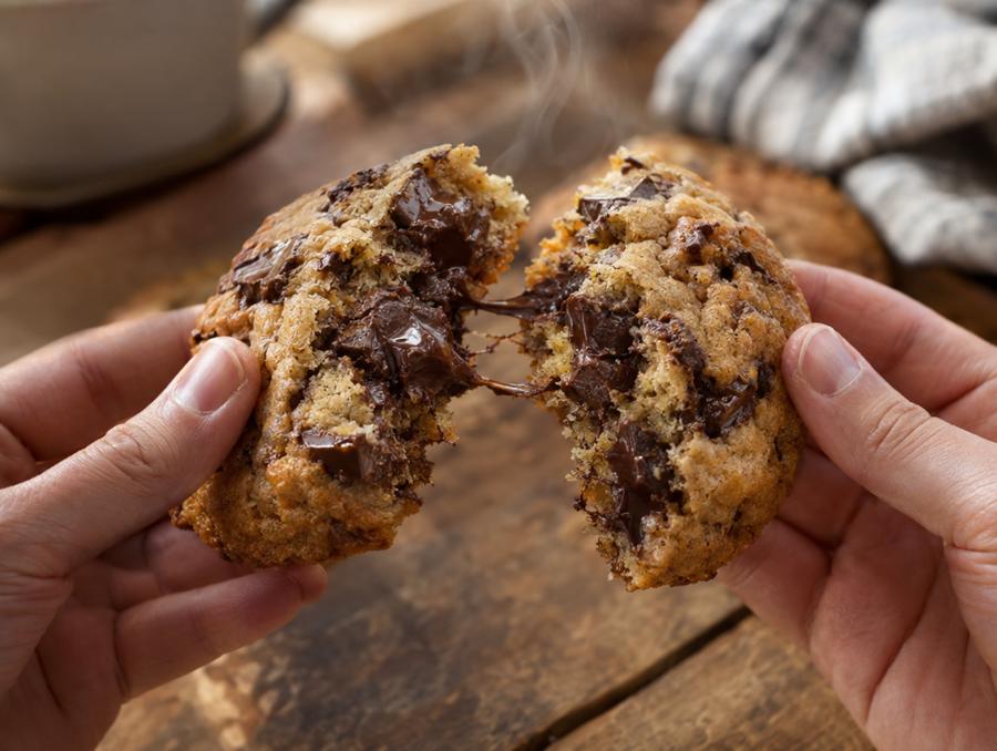 A chocolate chip cookie broken in half, soft in the middle with melted dark chocolate